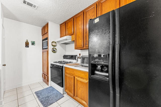 kitchen featuring white gas range, built in microwave, a textured ceiling, black fridge with ice dispenser, and light tile patterned floors