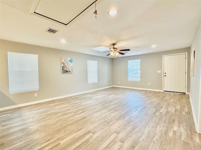 unfurnished room with ceiling fan, light wood-type flooring, and a textured ceiling