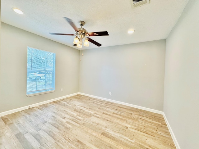 spare room with a textured ceiling, light wood-type flooring, and ceiling fan