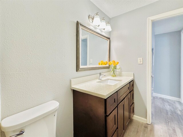 bathroom with toilet, a textured ceiling, vanity, and hardwood / wood-style floors