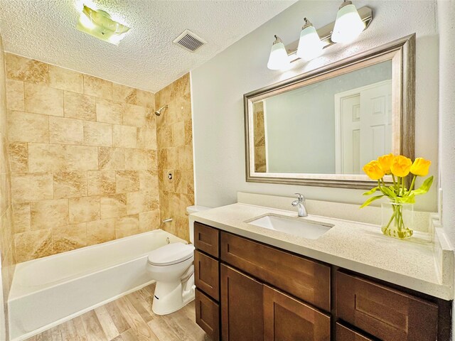 full bathroom with toilet, a textured ceiling, tiled shower / bath combo, wood-type flooring, and vanity