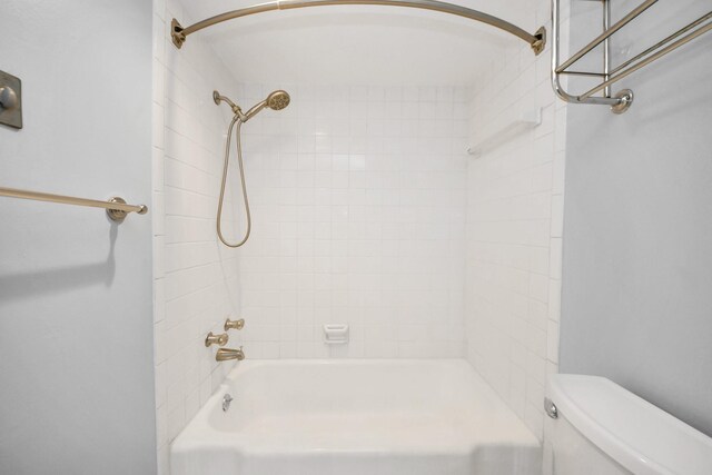 bathroom featuring toilet and tiled shower / bath