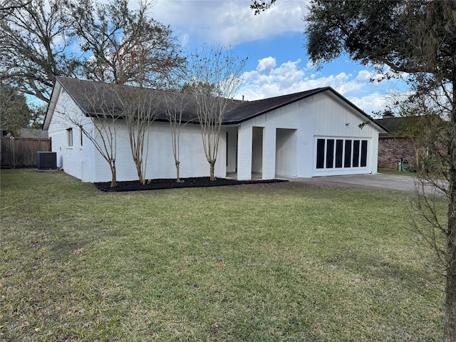 rear view of property featuring a lawn, central AC, and a garage