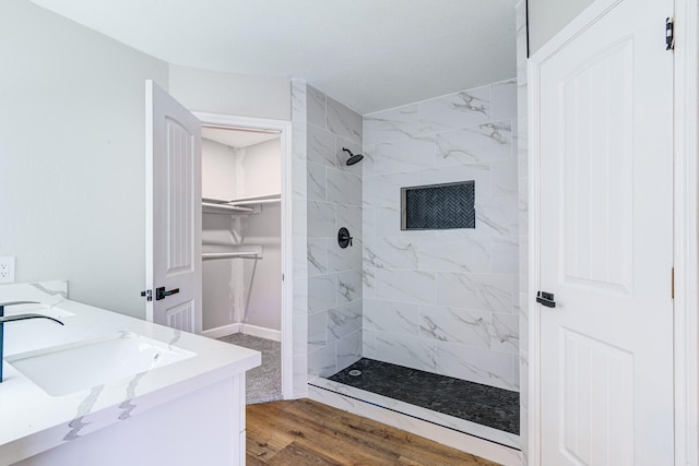 bathroom featuring tiled shower, hardwood / wood-style flooring, and vanity