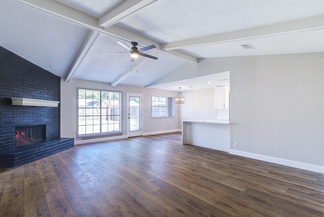 unfurnished living room with dark wood-type flooring, a textured ceiling, lofted ceiling with beams, and a fireplace