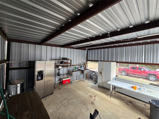 garage featuring stainless steel refrigerator with ice dispenser and white refrigerator with ice dispenser