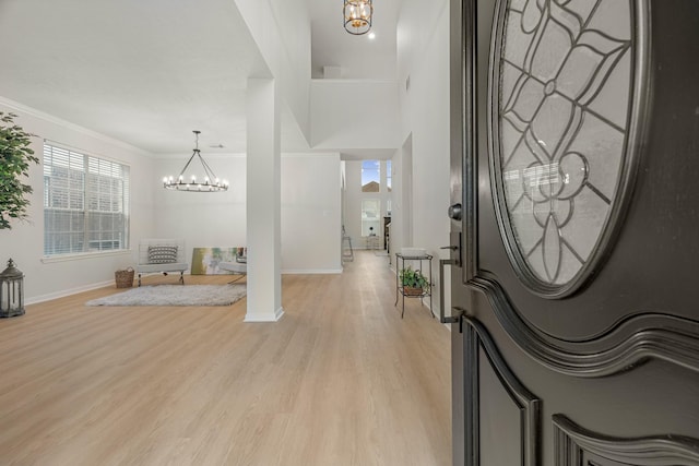 foyer entrance with light hardwood / wood-style floors, ornamental molding, and an inviting chandelier