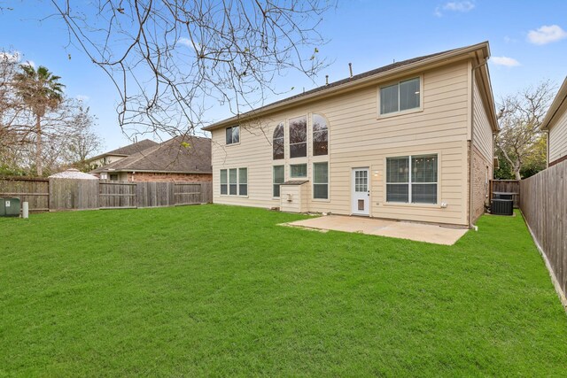 rear view of property featuring a yard, central AC, and a patio area