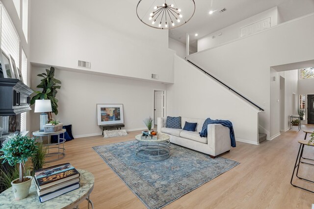 living room featuring light hardwood / wood-style flooring, a chandelier, and a high ceiling