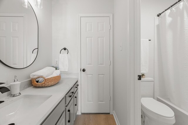 full bathroom with shower / bath combination with curtain, toilet, wood-type flooring, and vanity