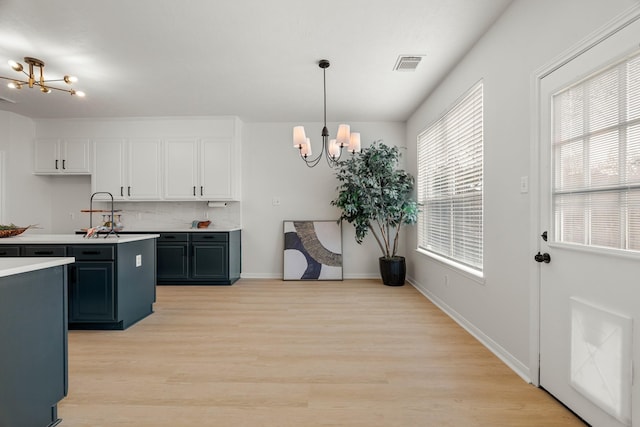 kitchen with white cabinets, tasteful backsplash, hanging light fixtures, and a chandelier