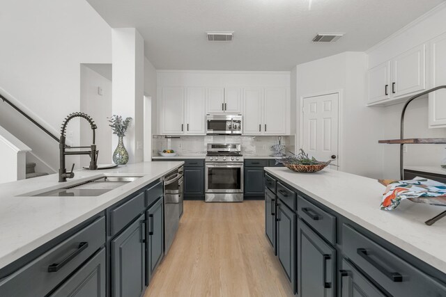 kitchen featuring white cabinets, stainless steel appliances, light hardwood / wood-style flooring, and sink