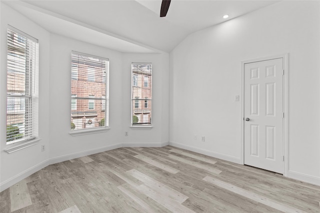 empty room with ceiling fan, light hardwood / wood-style flooring, and vaulted ceiling