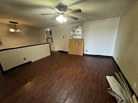 unfurnished room with ceiling fan with notable chandelier and dark hardwood / wood-style flooring