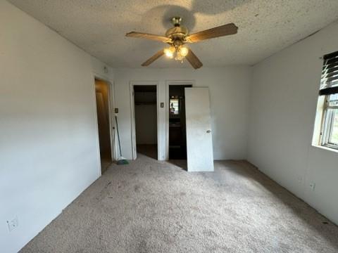 unfurnished bedroom featuring ceiling fan, carpet floors, and a textured ceiling