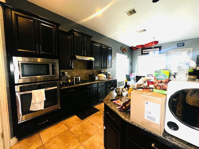 kitchen featuring decorative backsplash, light stone counters, light tile patterned floors, and appliances with stainless steel finishes