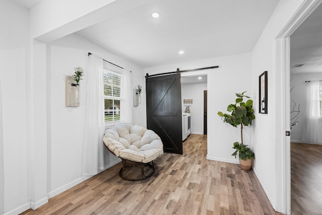 sitting room featuring a barn door and light hardwood / wood-style flooring