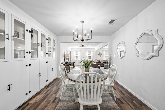 dining space with dark hardwood / wood-style flooring and an inviting chandelier