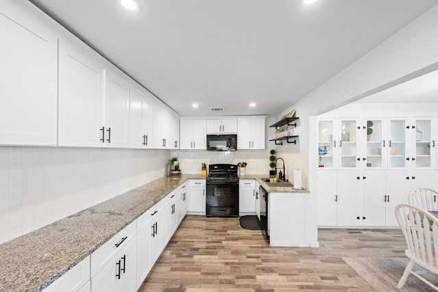 kitchen with backsplash, black appliances, white cabinets, light hardwood / wood-style flooring, and light stone countertops