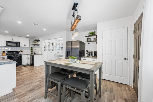 kitchen featuring black appliances, white cabinets, sink, light wood-type flooring, and tasteful backsplash