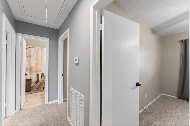 corridor with light carpet and a textured ceiling