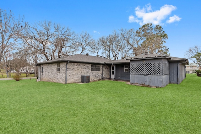 rear view of property with central AC unit and a lawn