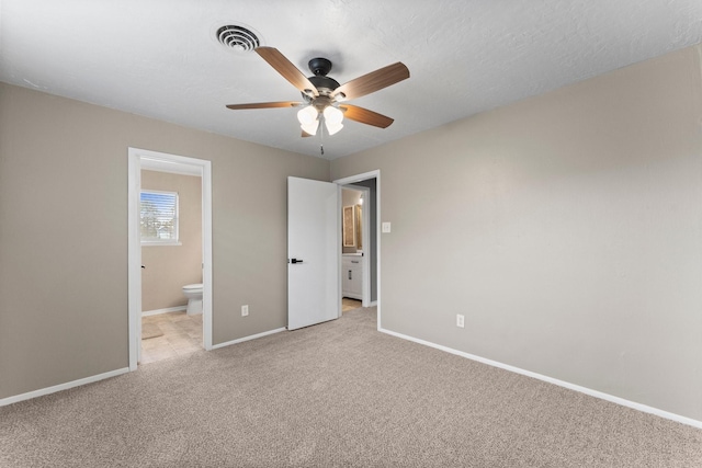 unfurnished bedroom featuring light carpet, connected bathroom, a textured ceiling, and ceiling fan