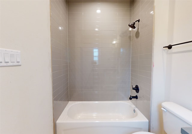 bathroom with tiled shower / bath combo and toilet