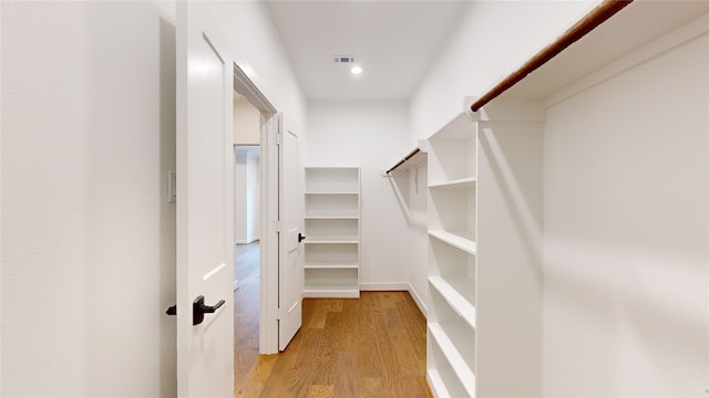 walk in closet with light hardwood / wood-style flooring