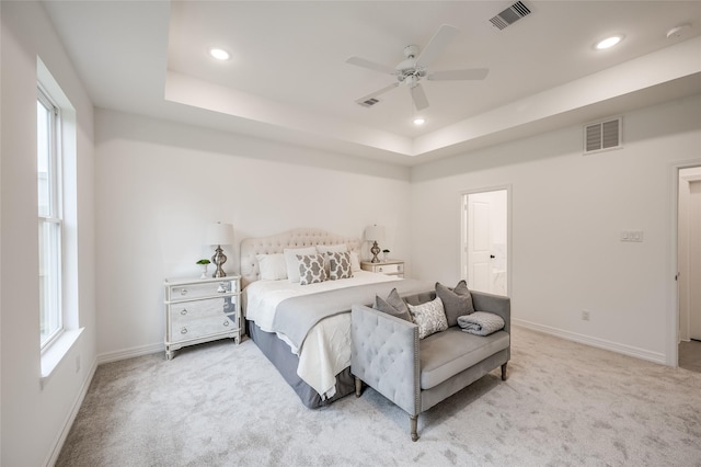 carpeted bedroom with multiple windows, a raised ceiling, and ceiling fan