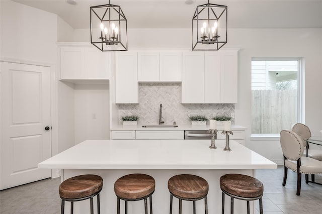 kitchen featuring hanging light fixtures, white cabinetry, a kitchen island with sink, and sink