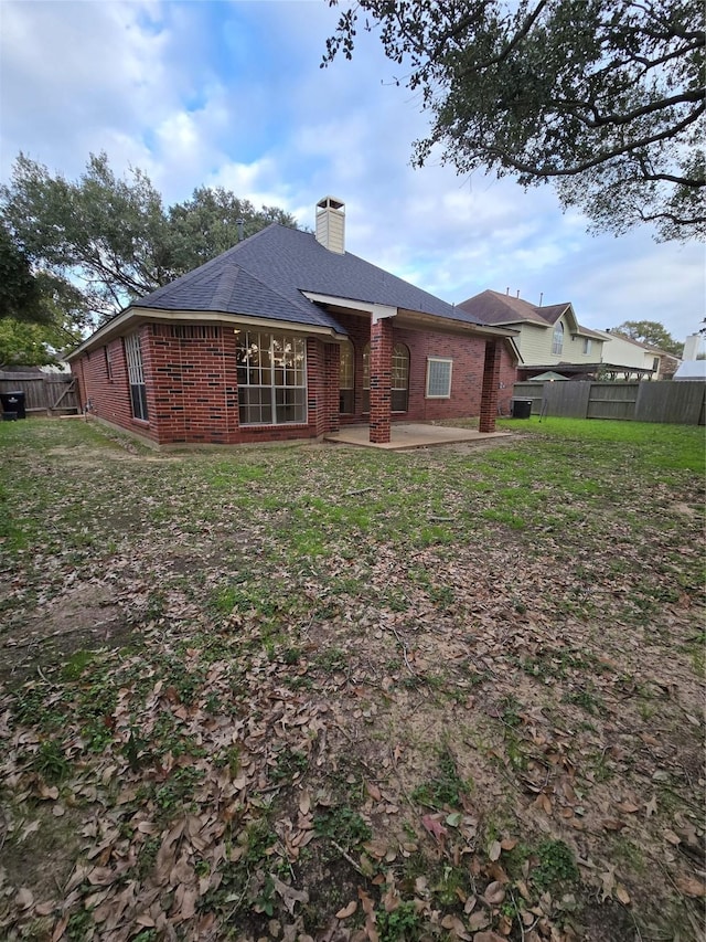 back of property with a lawn and a patio