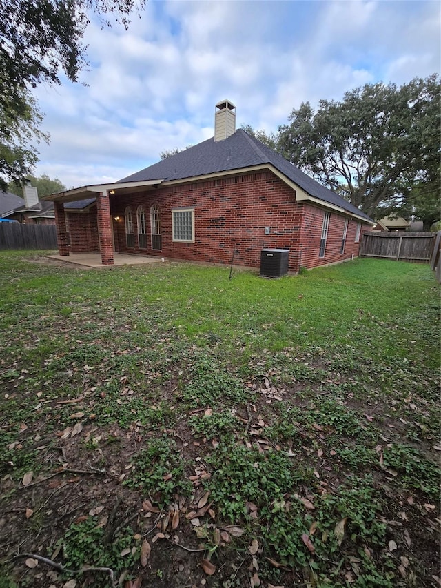 rear view of house featuring central air condition unit, a patio area, and a yard