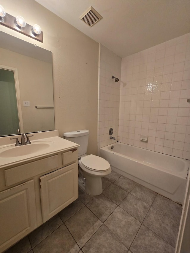 full bathroom featuring tile patterned floors, vanity, tiled shower / bath, and toilet