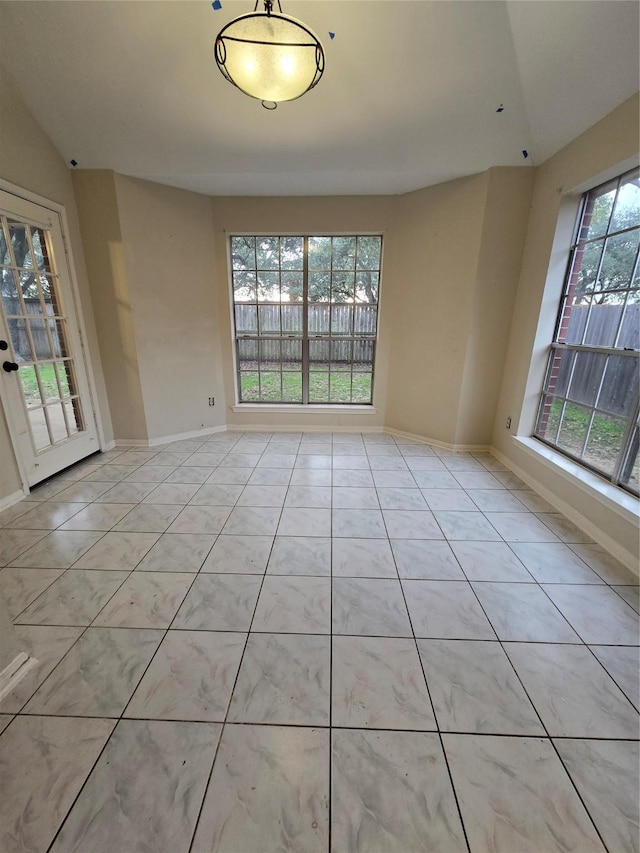 tiled empty room featuring lofted ceiling