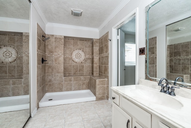 bathroom featuring vanity, tile patterned flooring, ornamental molding, a textured ceiling, and a tile shower