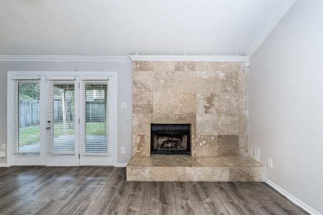 unfurnished living room featuring wood-type flooring, crown molding, and a tiled fireplace