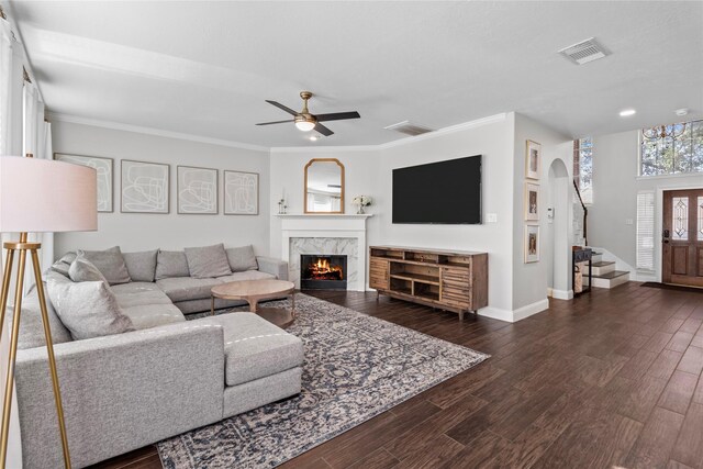 living room featuring dark hardwood / wood-style flooring, ceiling fan, ornamental molding, and a premium fireplace