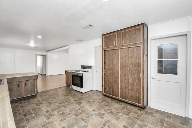 kitchen with white gas range and dark brown cabinetry