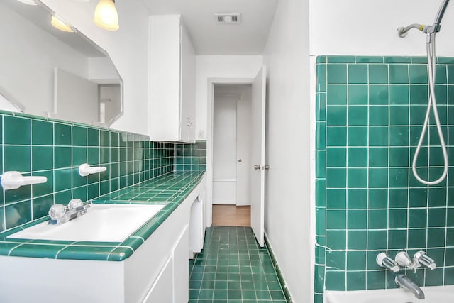 bathroom featuring backsplash, shower / washtub combination, vanity, and tile patterned flooring