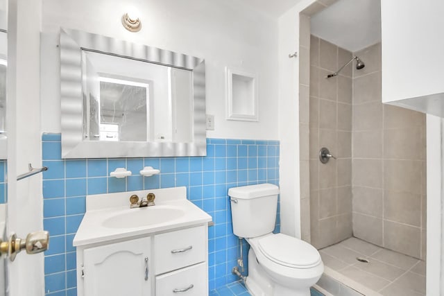 bathroom with tiled shower, vanity, toilet, and tile walls