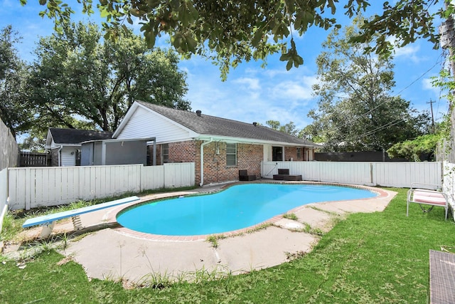 view of swimming pool featuring a lawn, a diving board, and a patio area