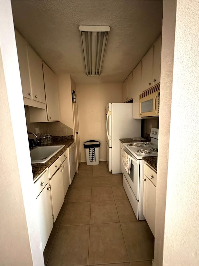 kitchen with decorative backsplash, white appliances, sink, tile patterned flooring, and white cabinetry