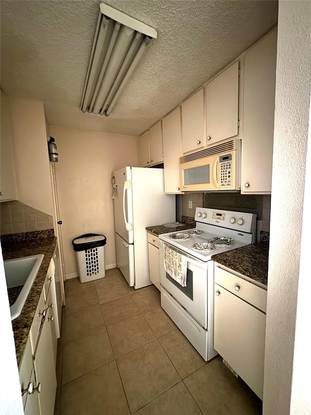 kitchen featuring sink, white cabinets, a textured ceiling, white appliances, and light tile patterned floors