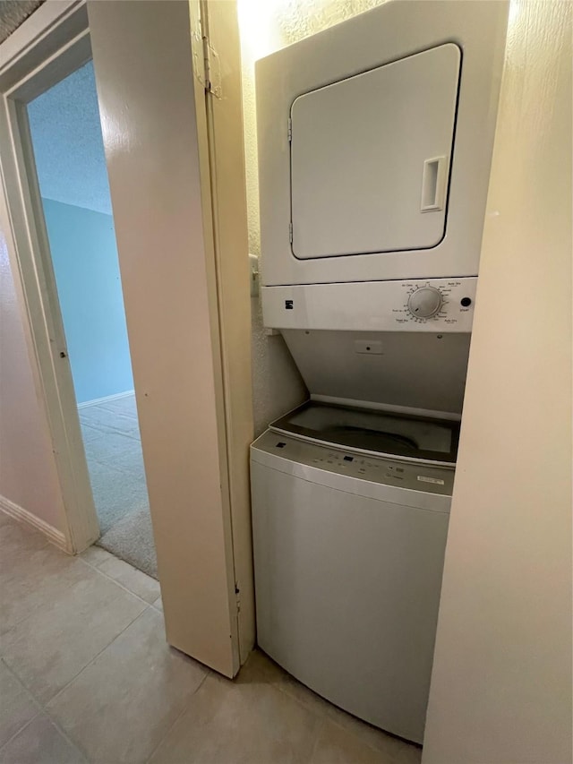 washroom with stacked washer and dryer and light tile patterned flooring