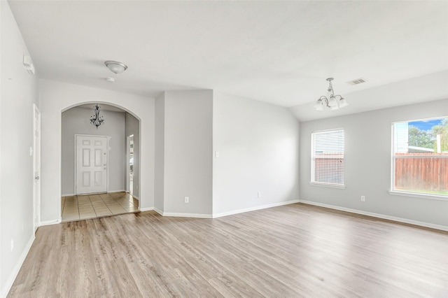 entrance foyer with light hardwood / wood-style floors, vaulted ceiling, and an inviting chandelier