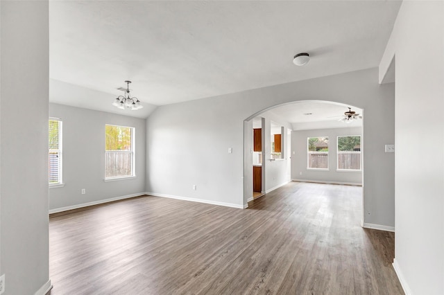 empty room with ceiling fan with notable chandelier, lofted ceiling, and hardwood / wood-style flooring