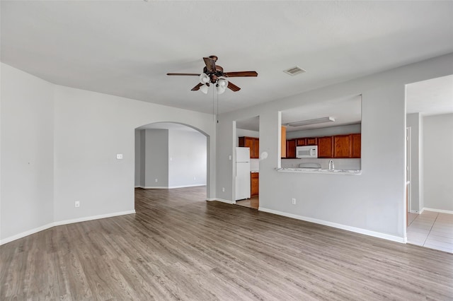 unfurnished living room with wood-type flooring and ceiling fan