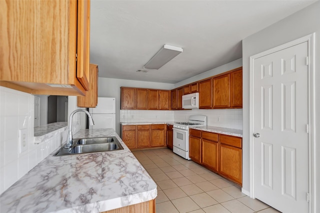 kitchen with backsplash, sink, light tile patterned floors, and white appliances