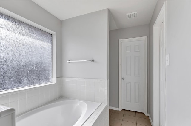 bathroom with tile patterned flooring and a relaxing tiled tub